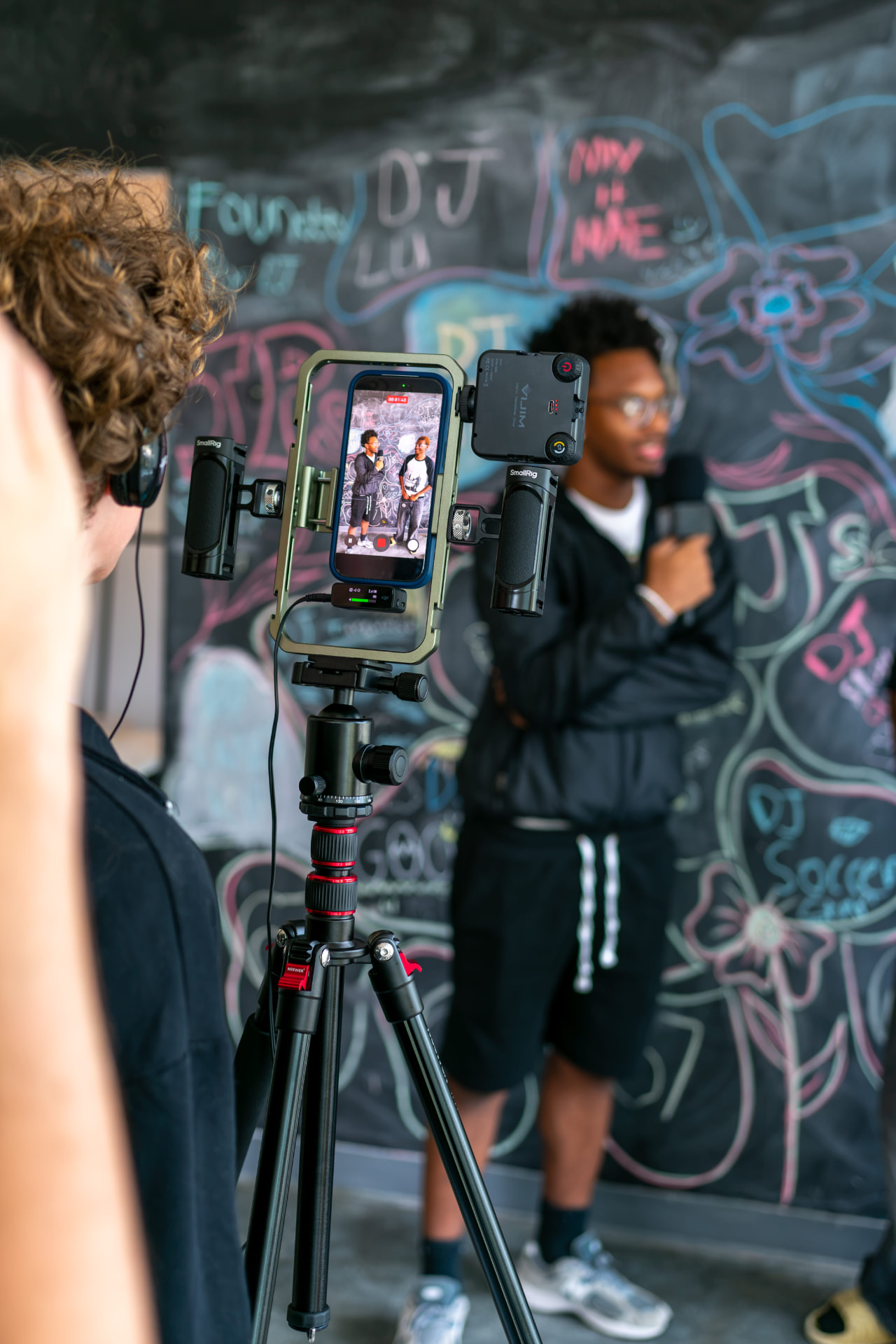 Students filming an interview against a chalkboard wall