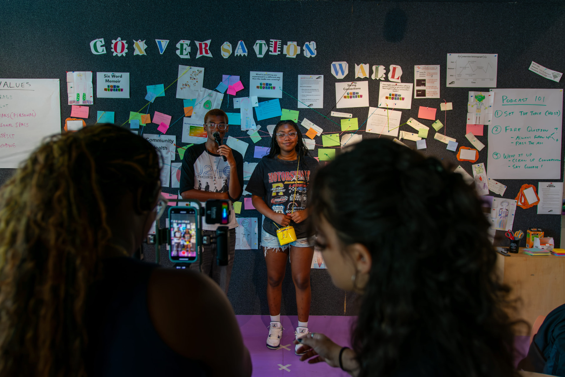 Students recording in front of the conversation wall